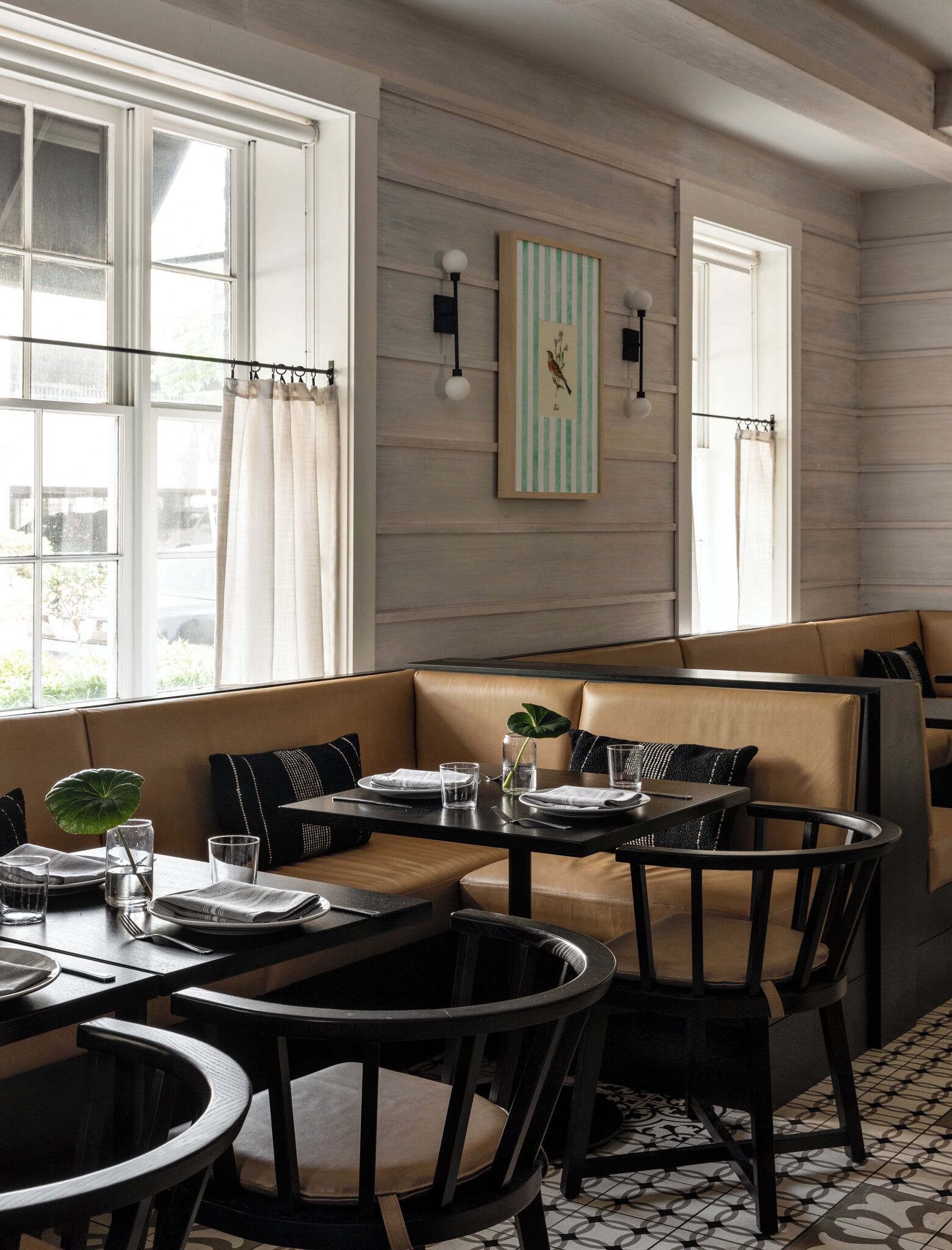 Un comedor con asientos tipo cabina, una mesa para dos personas y vistas al exterior a través de grandes ventanales.