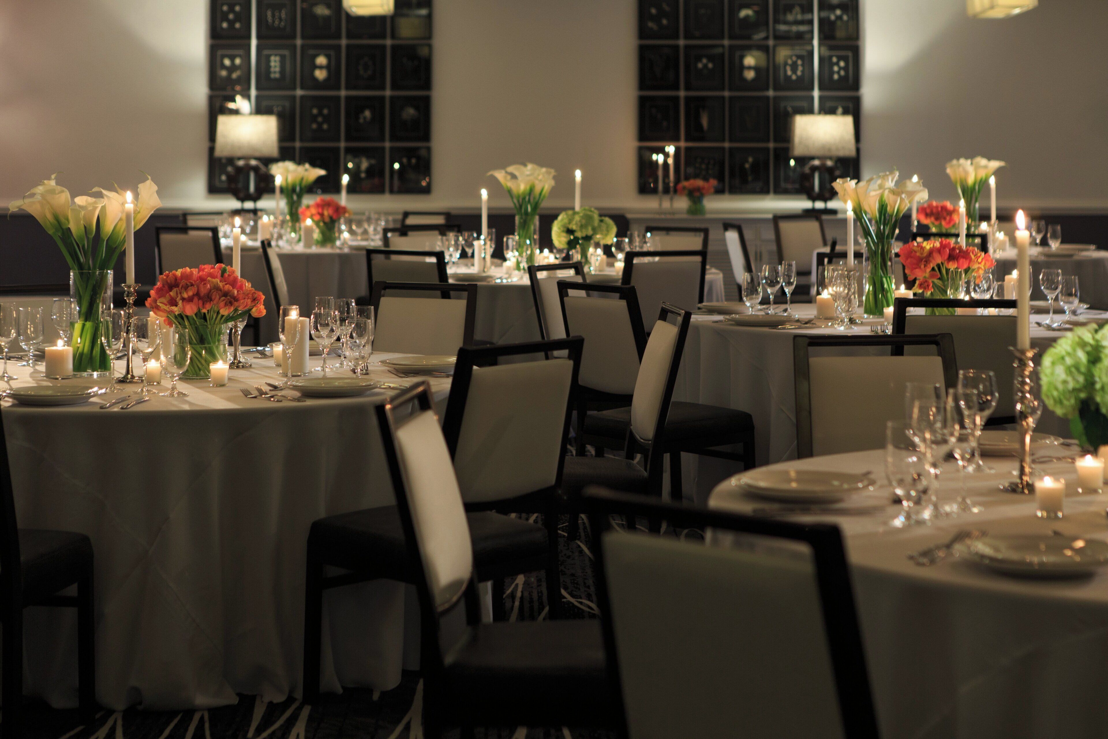 A restaurant with round tables set for dining, each with a candle and floral centerpiece.