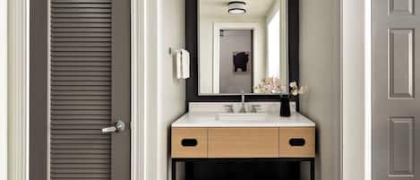 A modern bathroom with a white sink, black-framed mirror, and a towel rack.