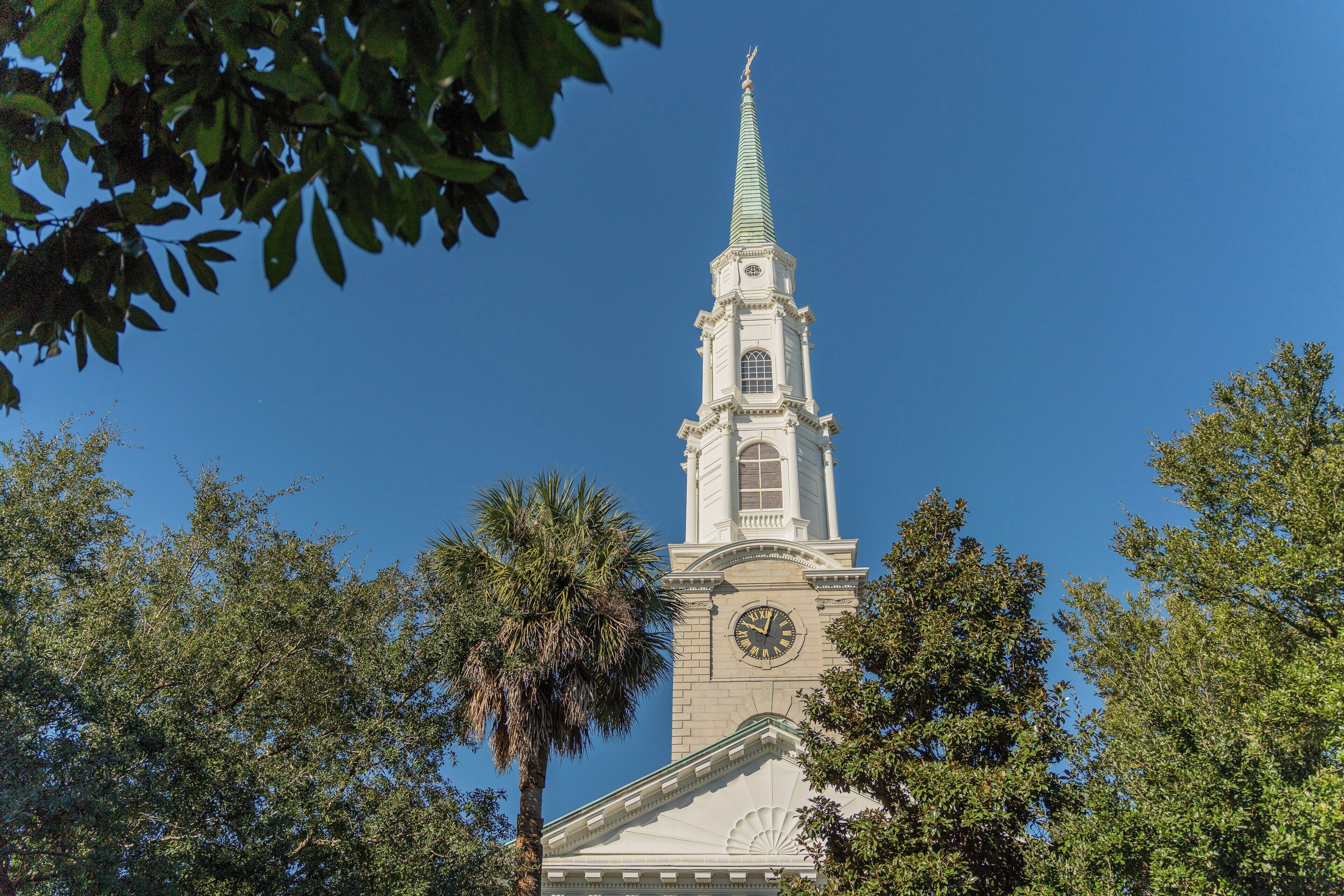 A church with a clock tower, surrounded by trees.