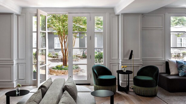 Un salón amplio con un gran ventanal corredero que da a un patio exterior.