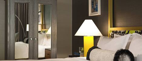 A hotel room with a bed, a nightstand, a lamp, a wardrobe, and a framed picture on the wall.