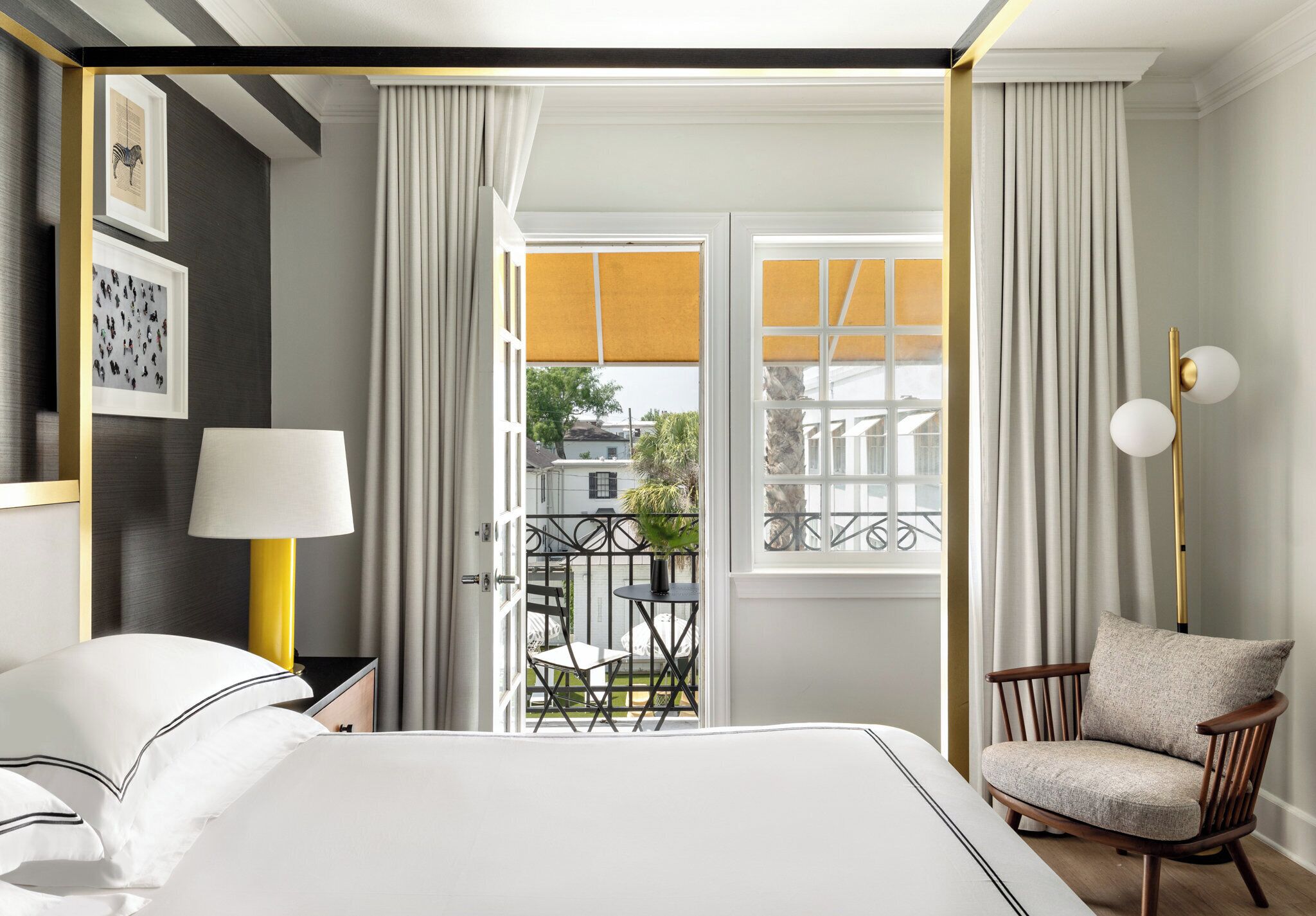 Une chambre d’hôtel avec un lit, une chaise, une table, une lampe et une vue sur l’extérieur.