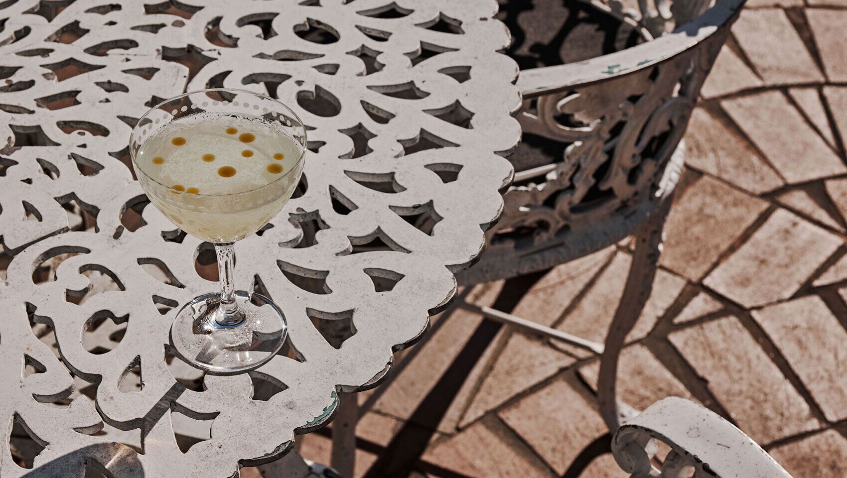 A table with a decorative metal pattern and a glass with a drink.
