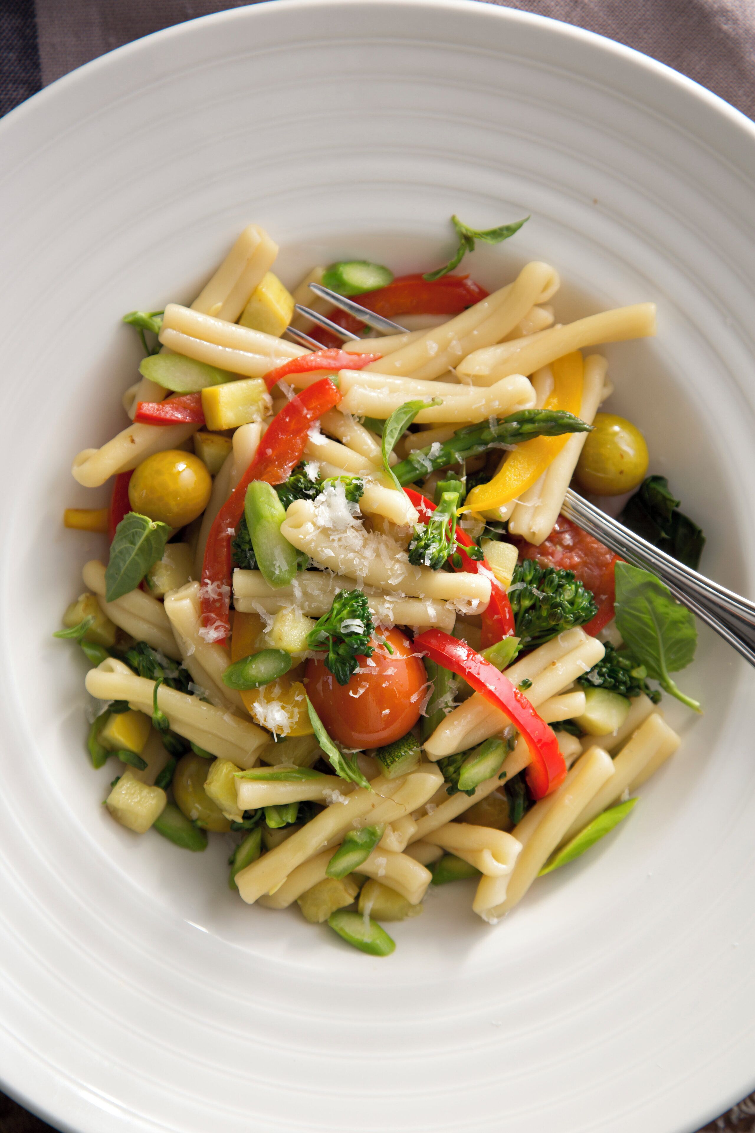 A white plate with pasta, vegetables, and a fork.