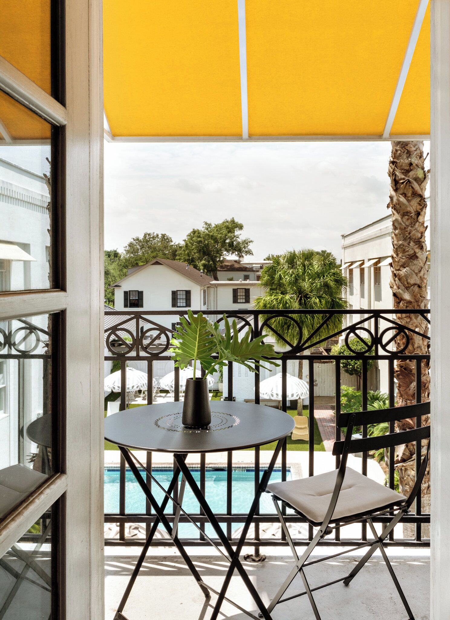 A balcony with a round table, a chair, and a potted plant.