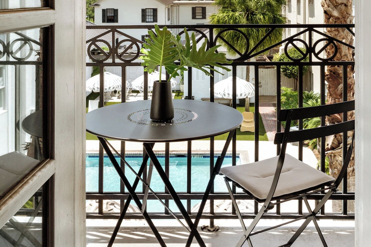 A balcony with a round table, a chair, and a potted plant.