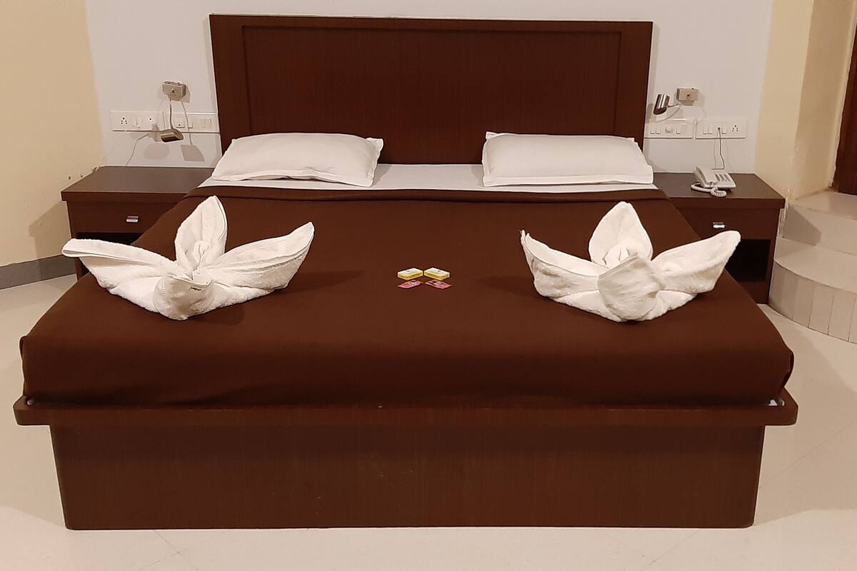 A neatly made bed with a brown headboard, two white pillows, and a white blanket.