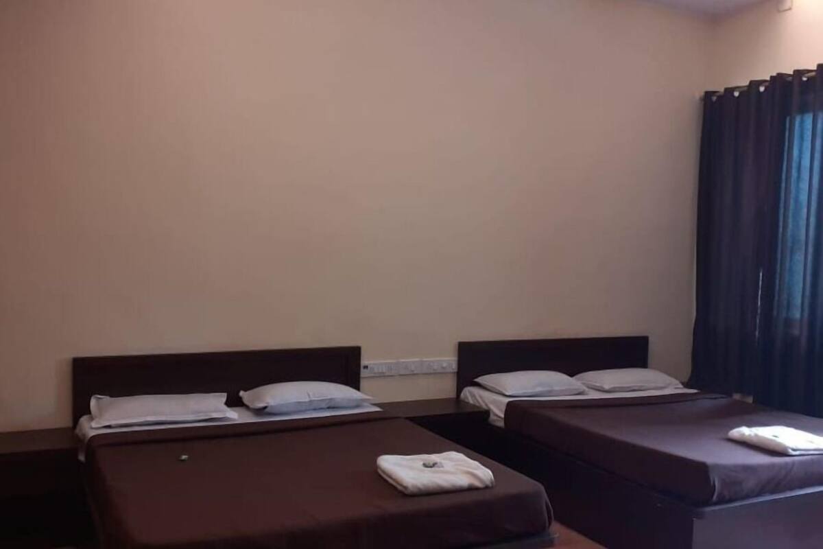 A hotel room with two single beds, each with a pillow and a folded towel.