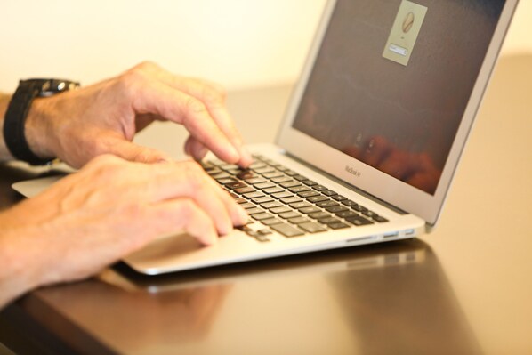 A person typing on a laptop with a visible screen displaying a coffee cup icon. - AmericInn by Wyndham Bemidji (Bemidji)