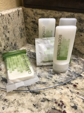 A countertop with a package of cleansing balm, a bottle of body lotion, and a container of makeup remover. - AmericInn by Wyndham Bemidji (Bemidji)