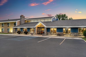 A hotel with a large entrance, a parking lot, and a clear sky.