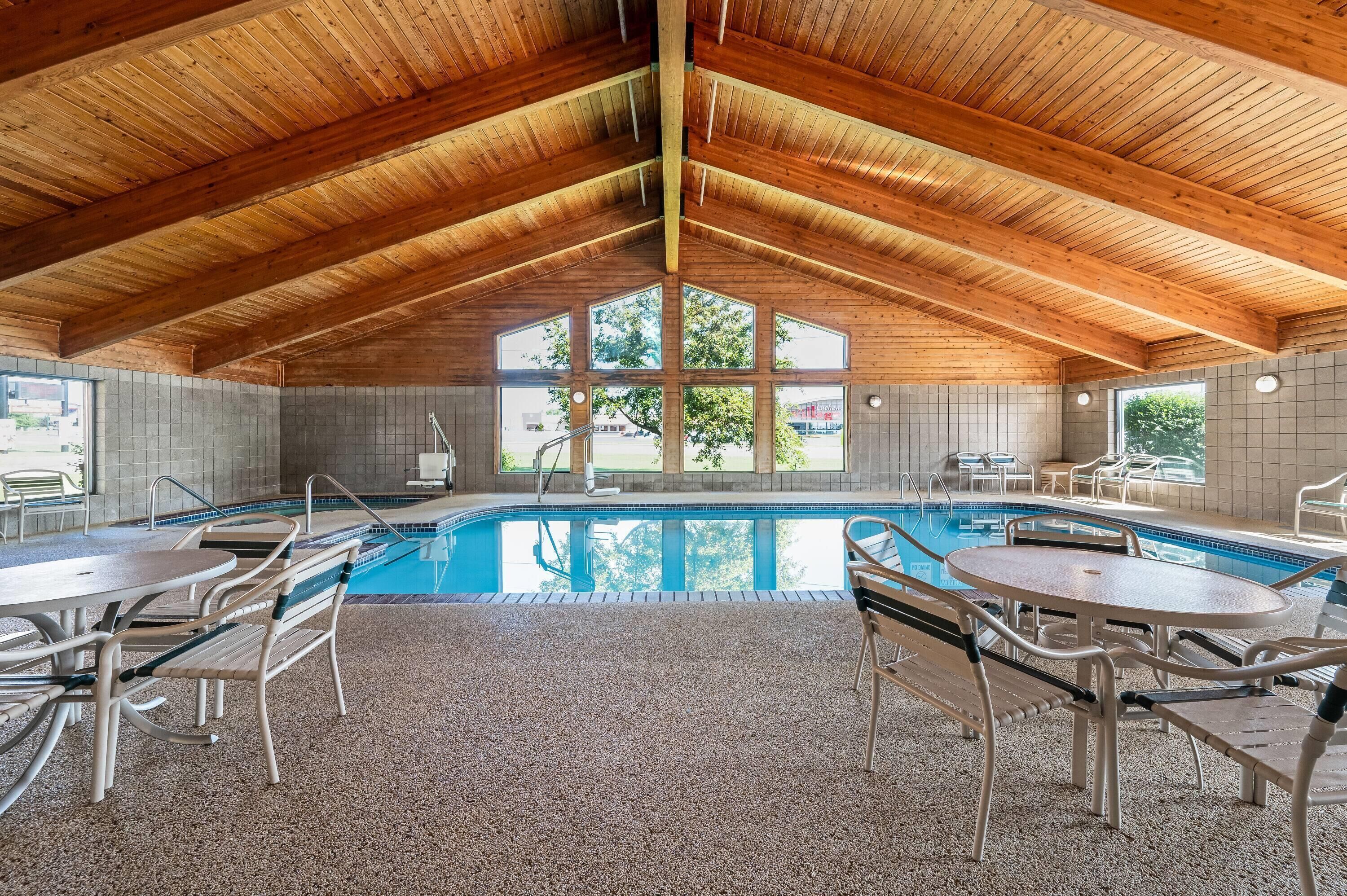Ein Hallenbad mit hoher Holzbalkendecke und mehreren Fenstern.