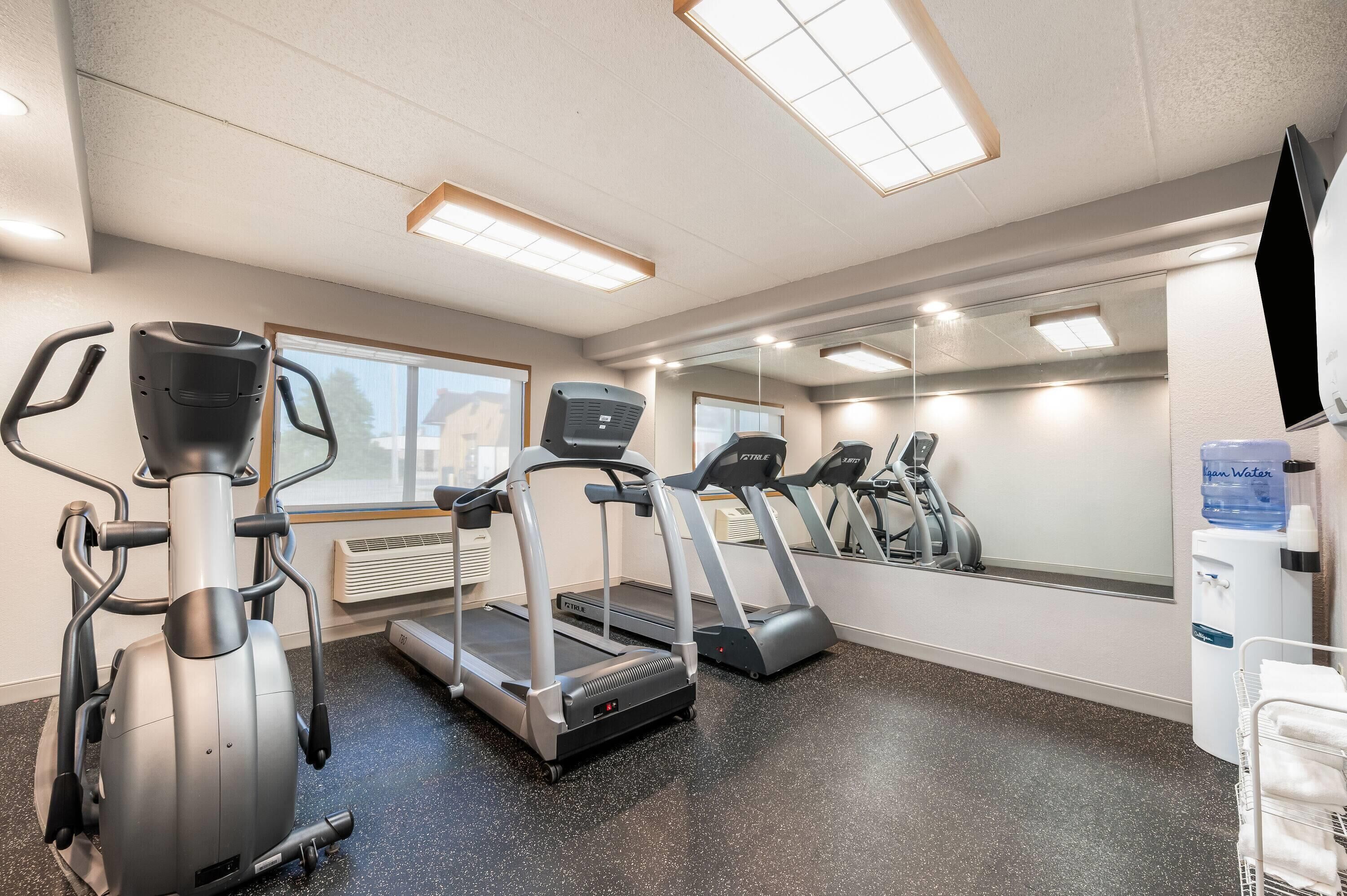 A gym with treadmills, an elliptical, and a water dispenser.