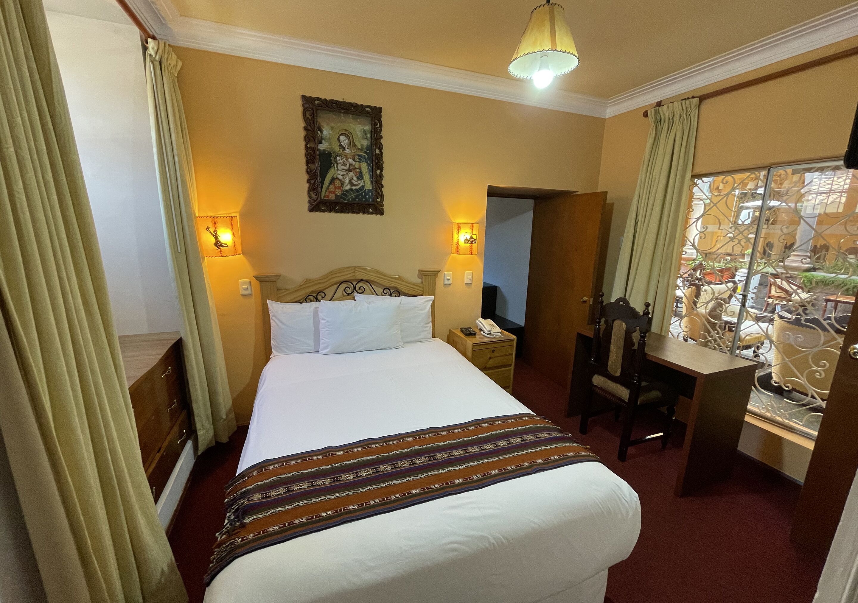 Una habitación de hotel con cama, lámparas de noche, escritorio y una silla.