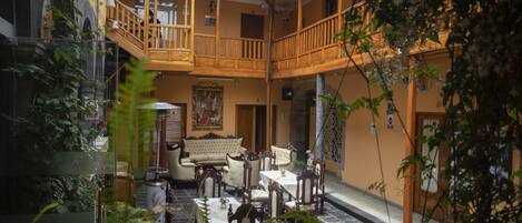 An indoor courtyard with a wooden balcony, seating area, and a fountain.