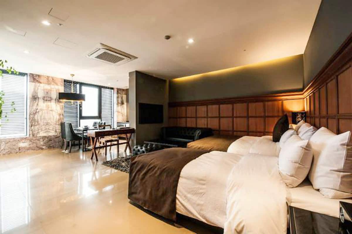 A modern bedroom with a large bed, a desk, and a TV.