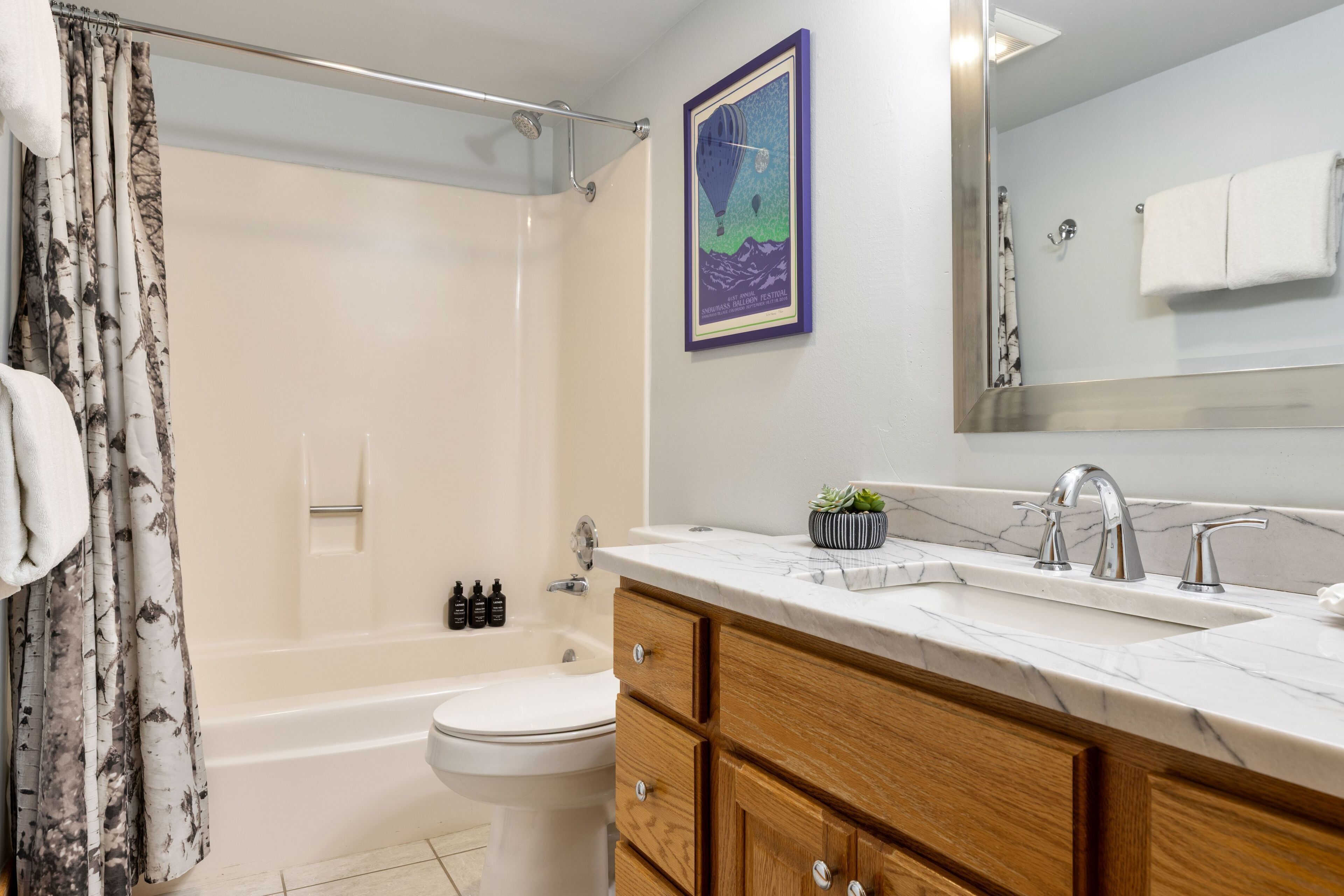 Une salle de bain équipée d’une baignoire, de toilettes, d’un meuble-lavabo avec un miroir et d’un rideau de douche.