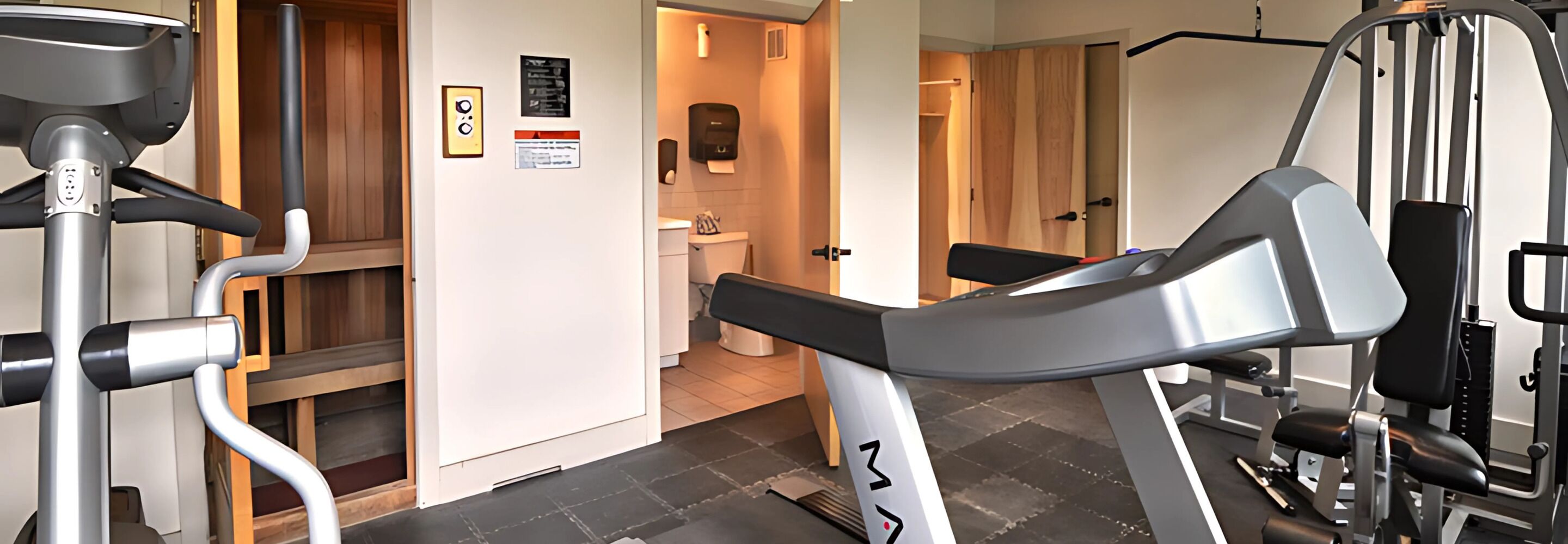 Une salle de sport équipée de matériel d’exercice, une porte en bois et un panneau sur le mur.