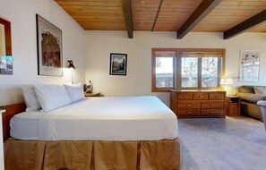 A bedroom with a large bed, a dresser, a nightstand, and a window with a view of trees. - Aspenwood - CoralTree Residence Collection (Snowmass Village)