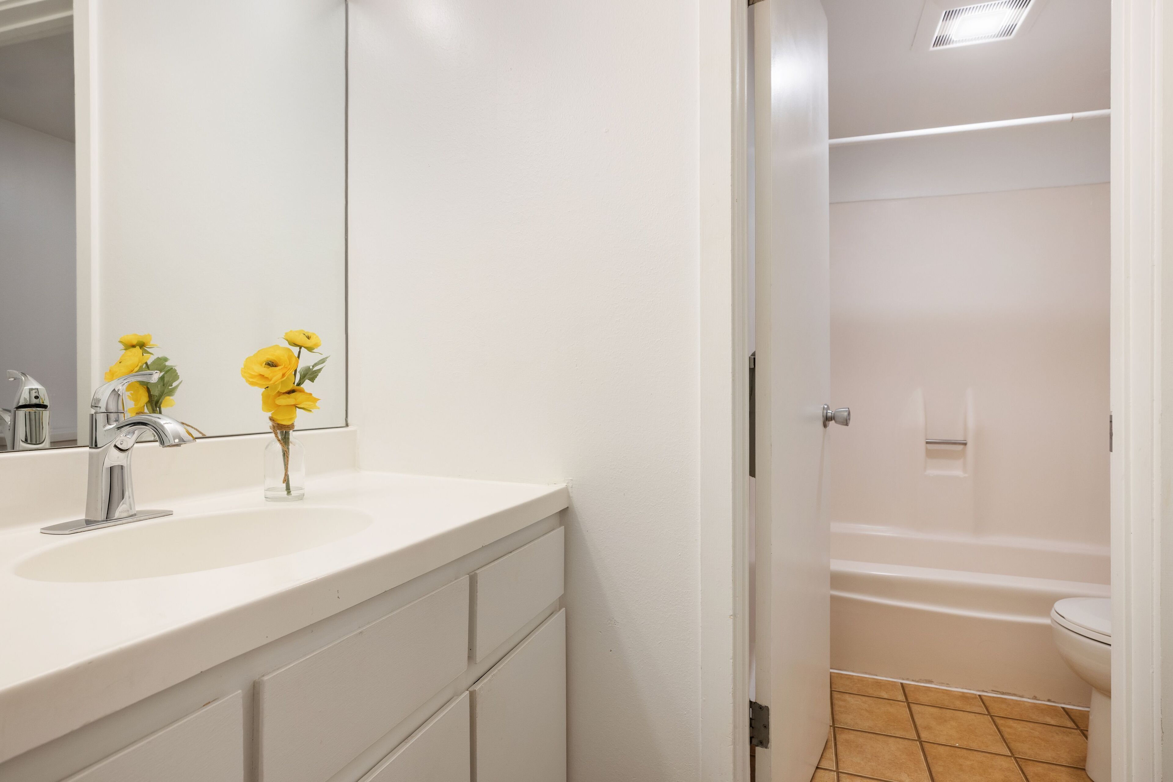 A bathroom with a white sink, mirror, and a shower area.