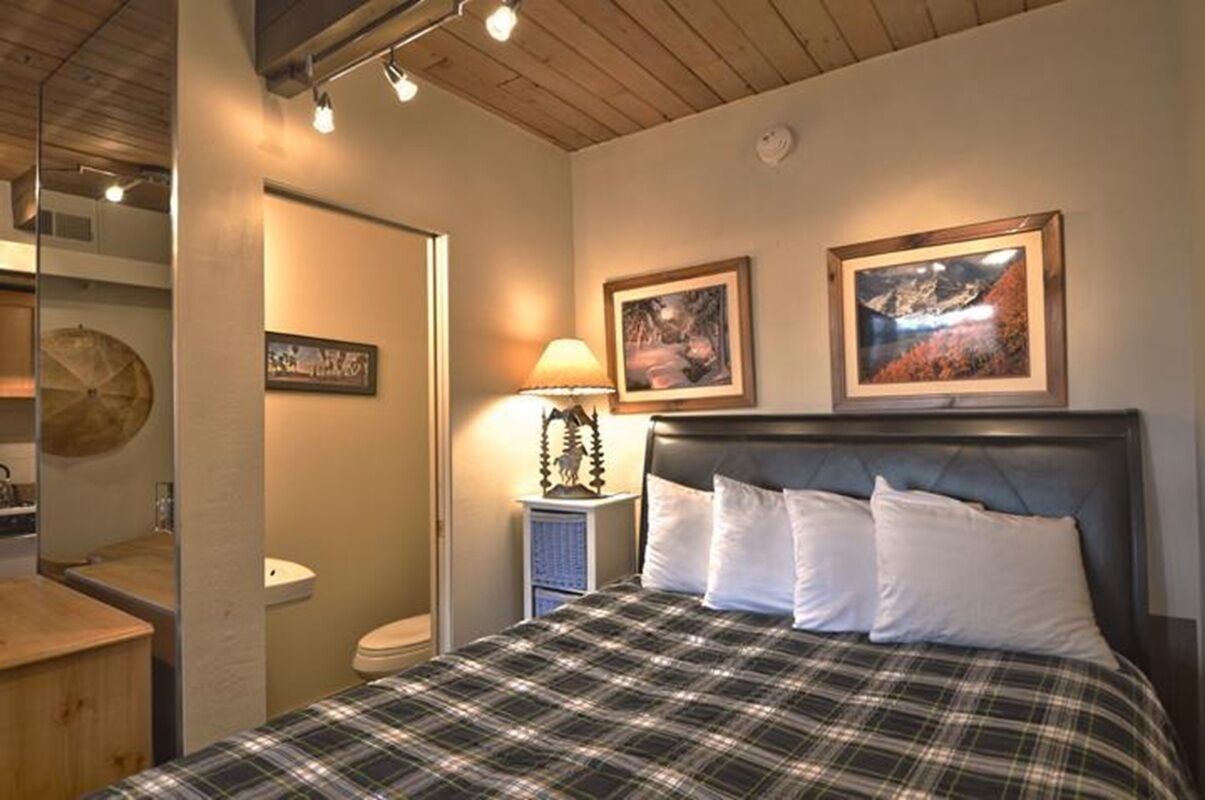 A bedroom with a bed, a nightstand with a lamp, and two framed pictures on the wall.