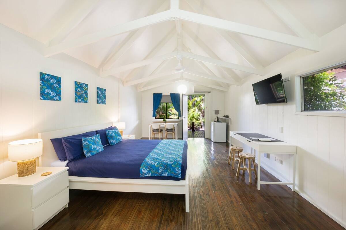 Een slaapkamer met een bed, bureau en televisie.