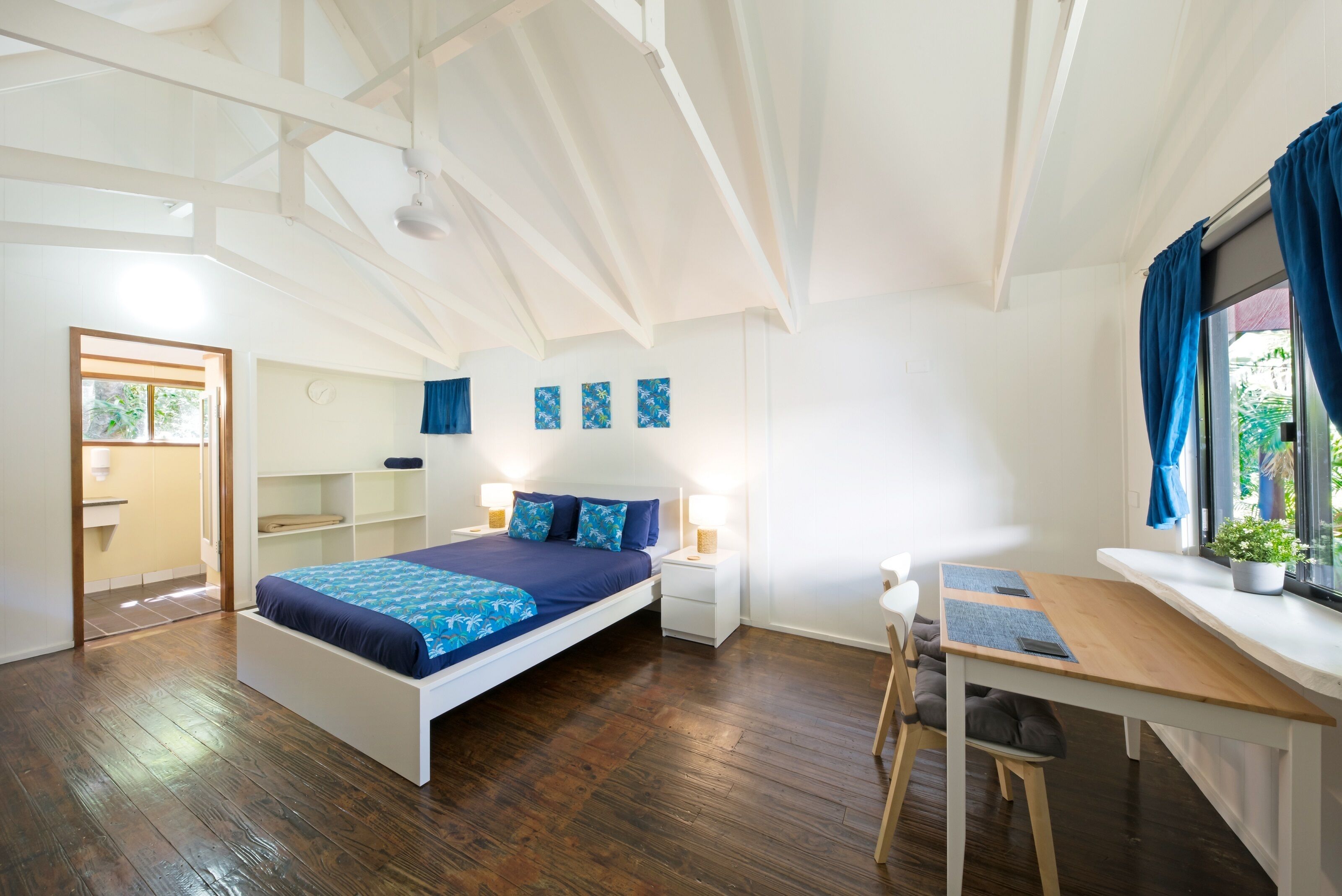 Een moderne slaapkamer met een groot bed, een bureau en een raam met gordijnen.