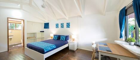 A modern bedroom with a large bed, a desk, and a window with curtains.