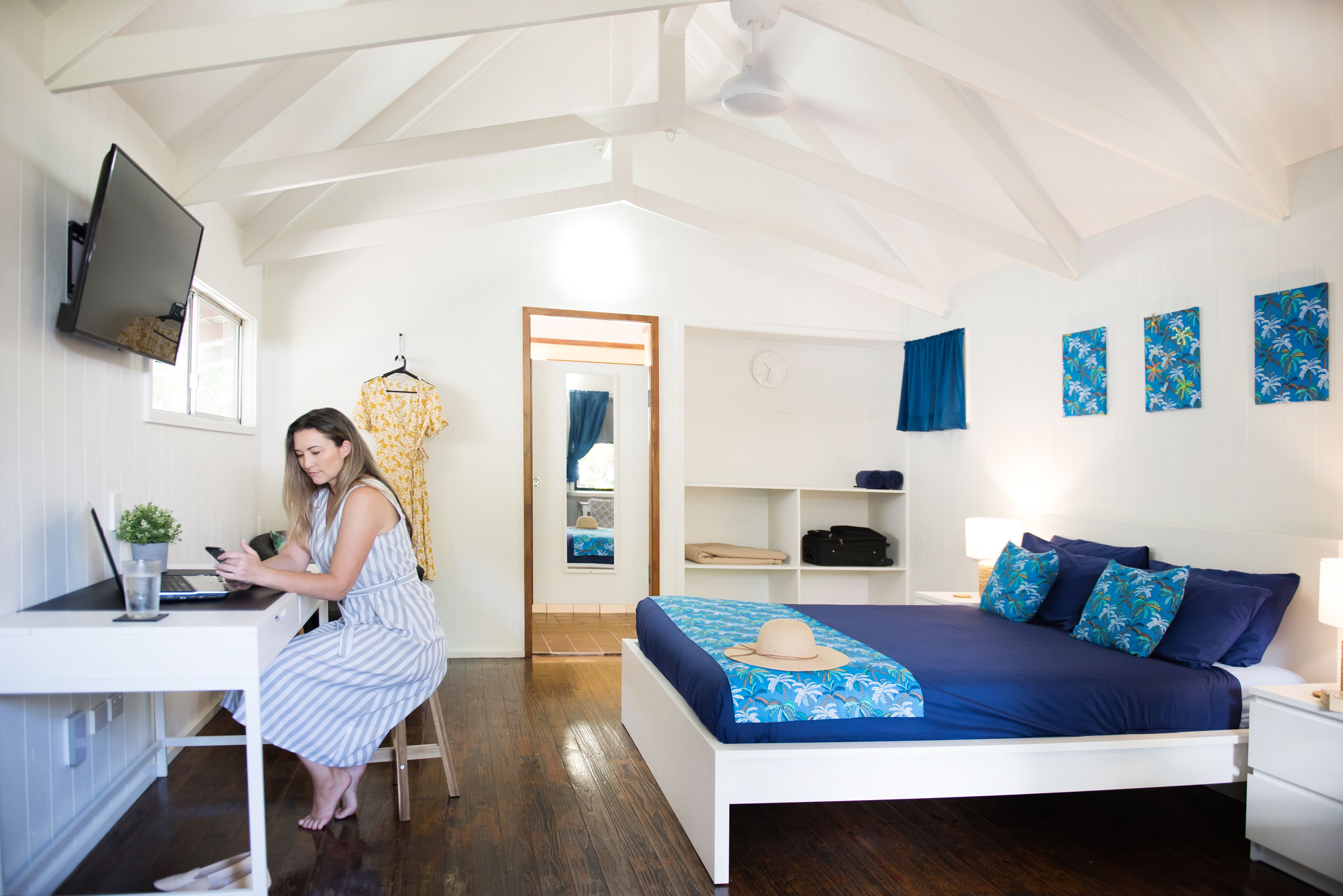 Una habitación con cama, escritorio, silla, televisor y armario.