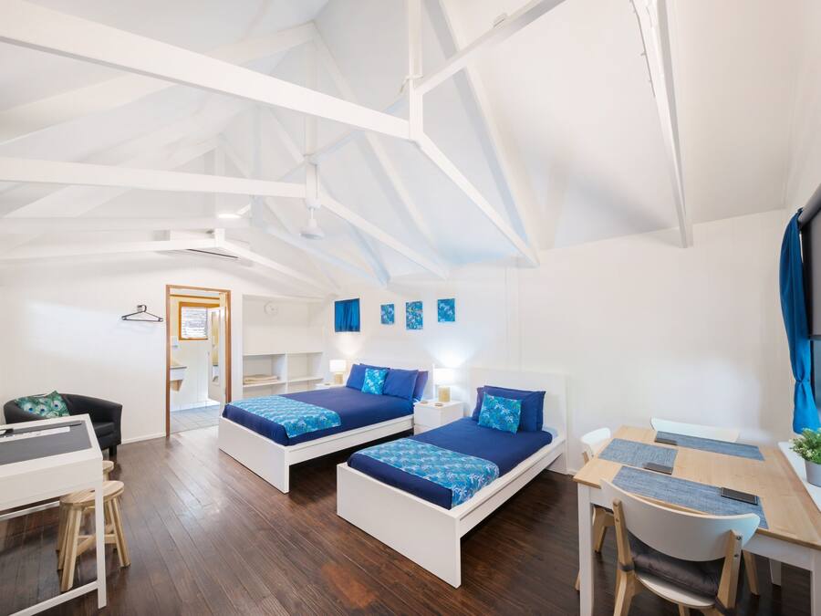 A modern room with two beds, a desk, and a chair.