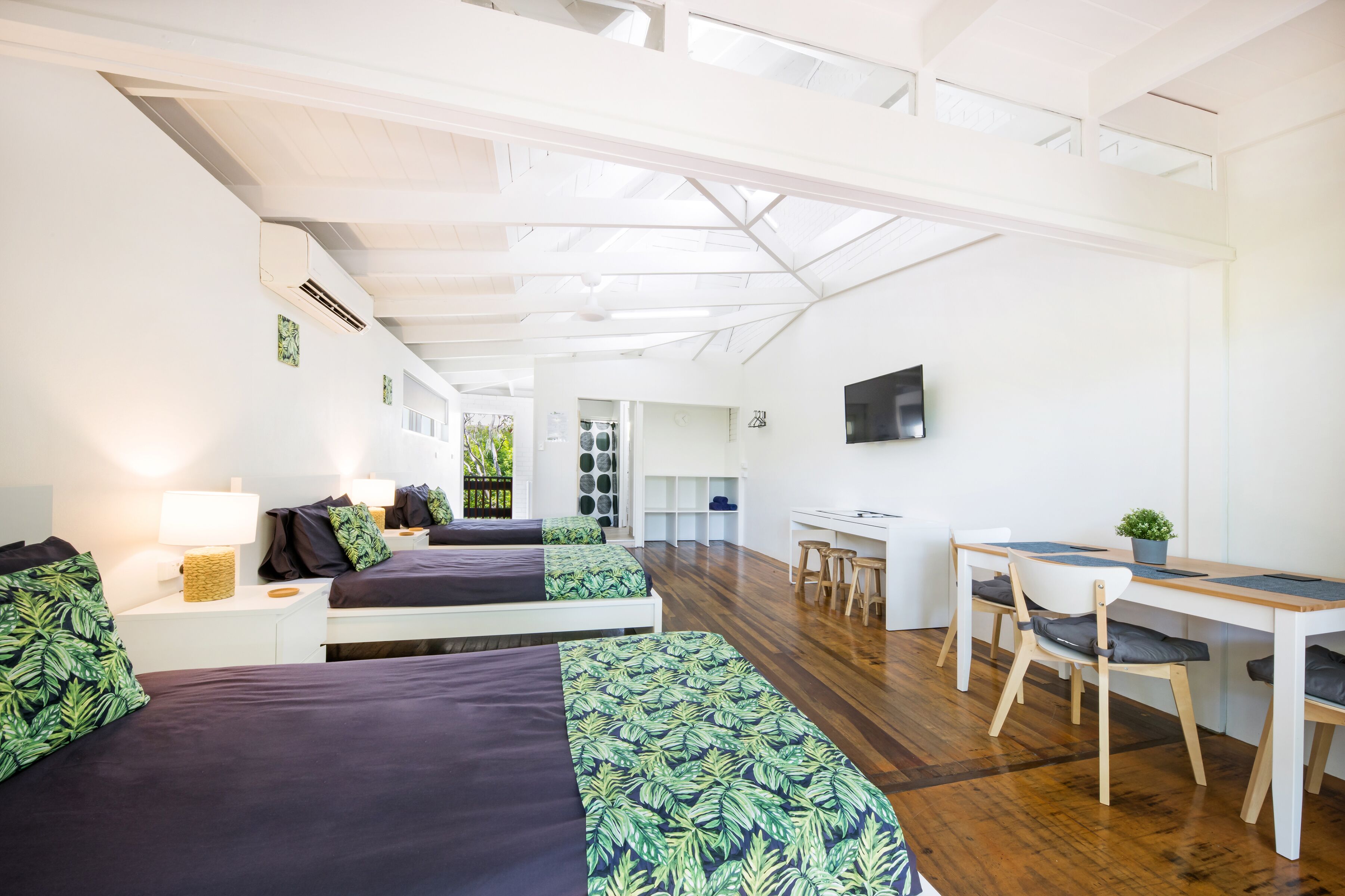 A modern hotel room with two beds, a desk, and a TV.