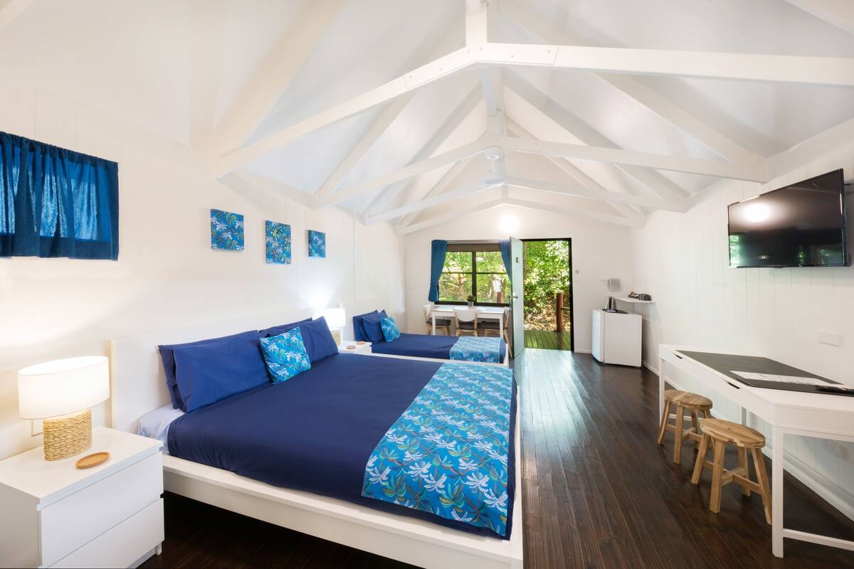 Een slaapkamer met twee bedden, een bureau en een televisie.