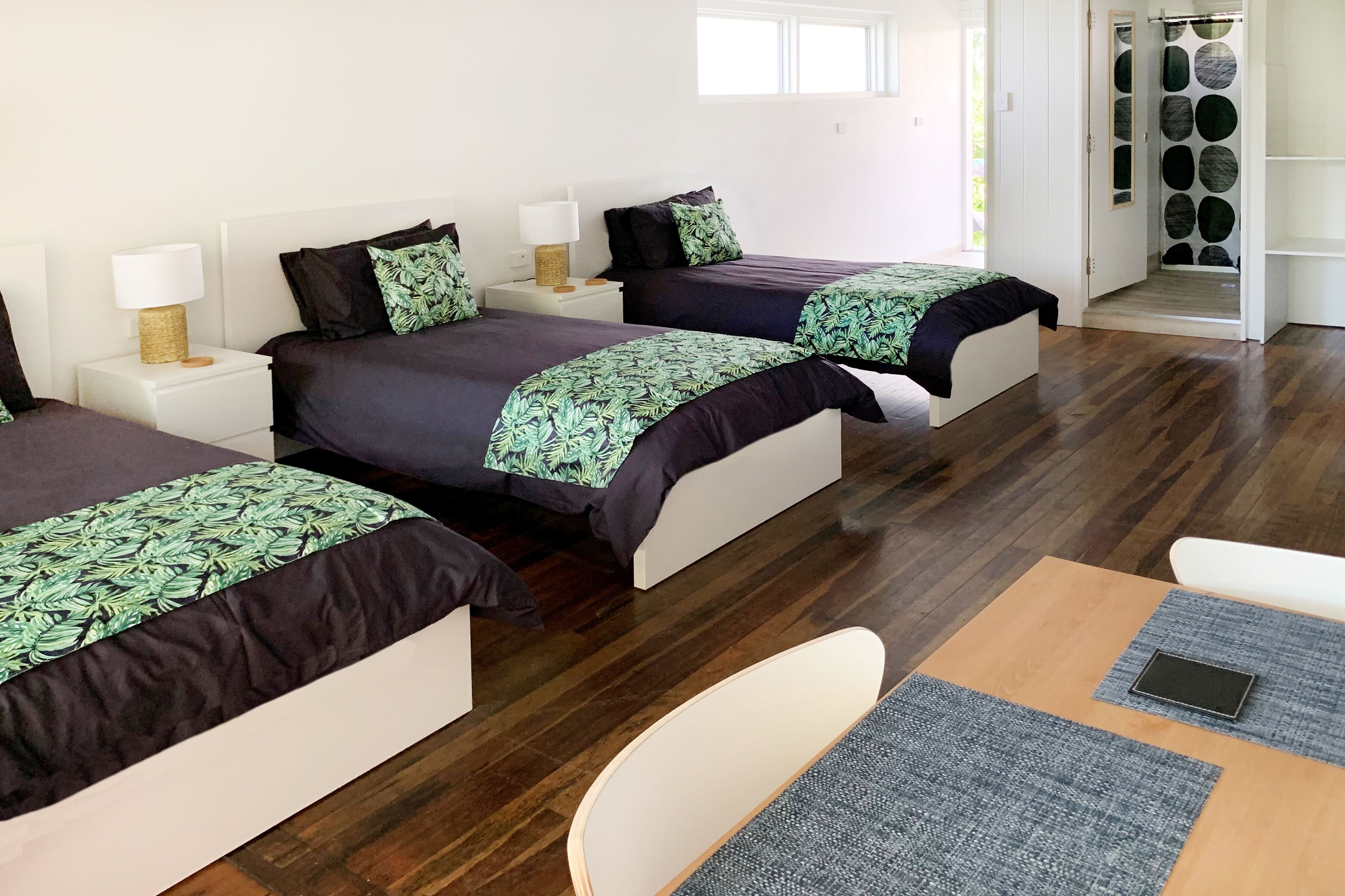 A hotel room with two beds, a small table, and a chair.