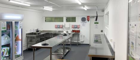 A modern kitchen with stainless steel appliances, a long counter, and a refrigerator.