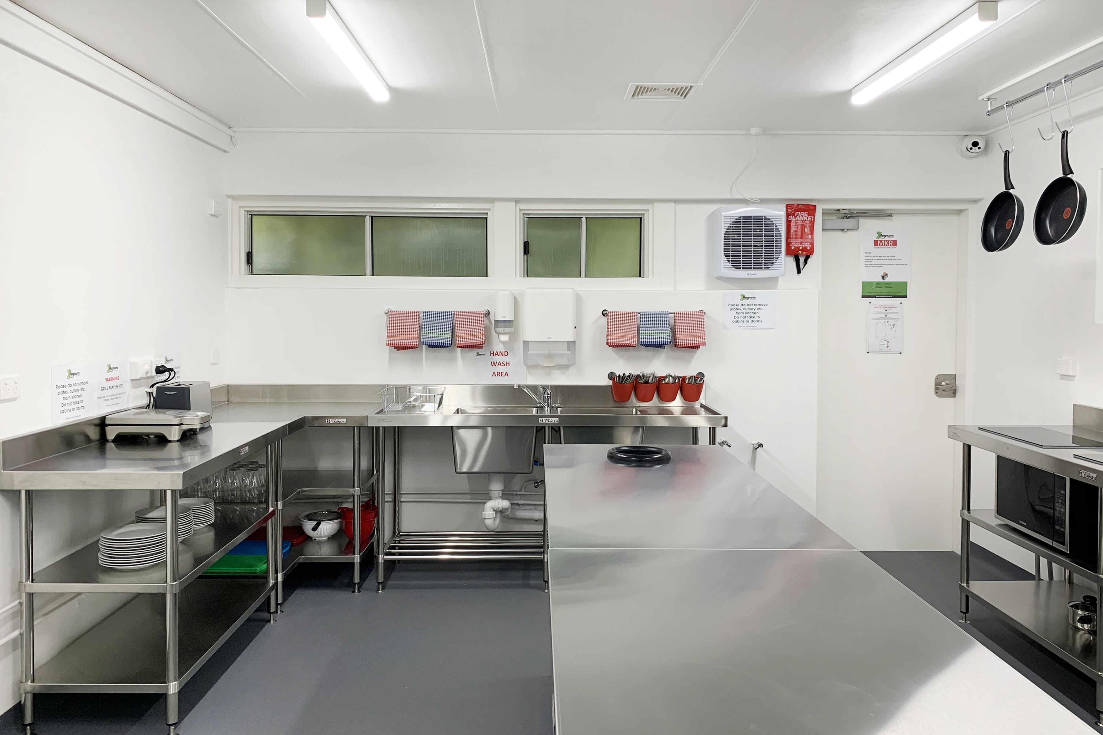 A modern kitchen with stainless steel appliances, a hand washing station, and a microwave.