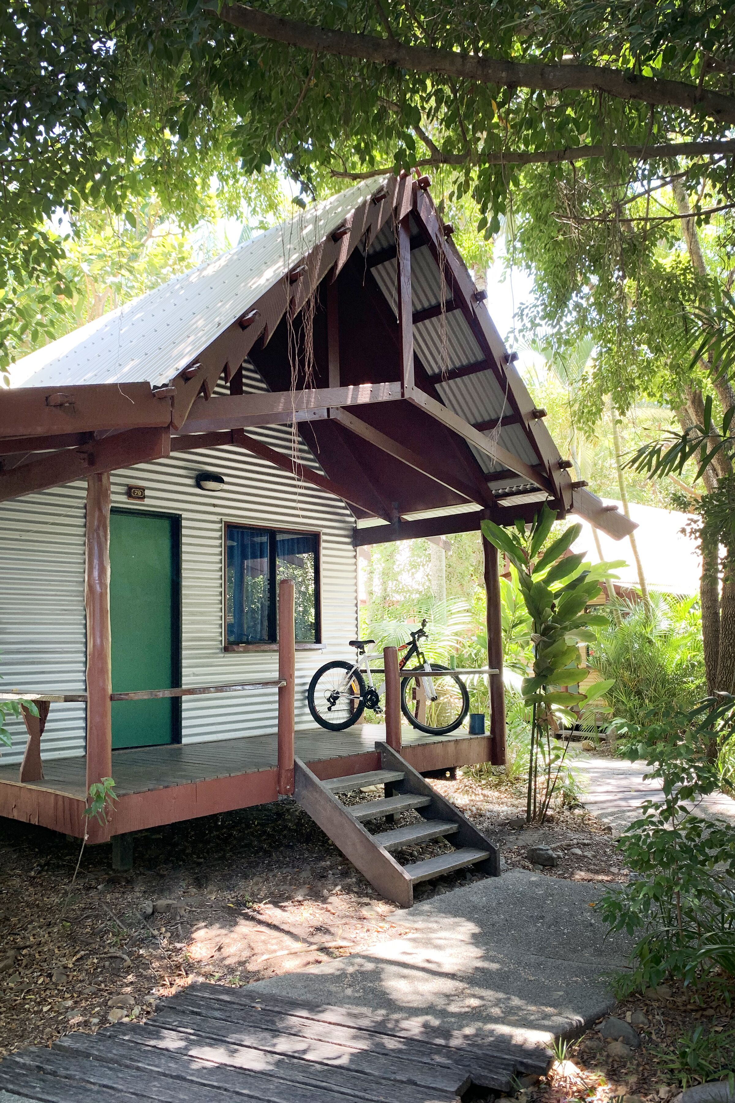 A rustic cabin with a metal roof, a green door, and a bicycle parked outside.
