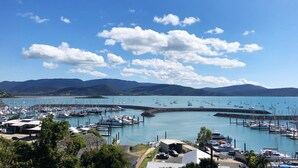 Ein Yachthafen mit vertäuten Booten, umgeben von Hügeln und blauem Himmel.
