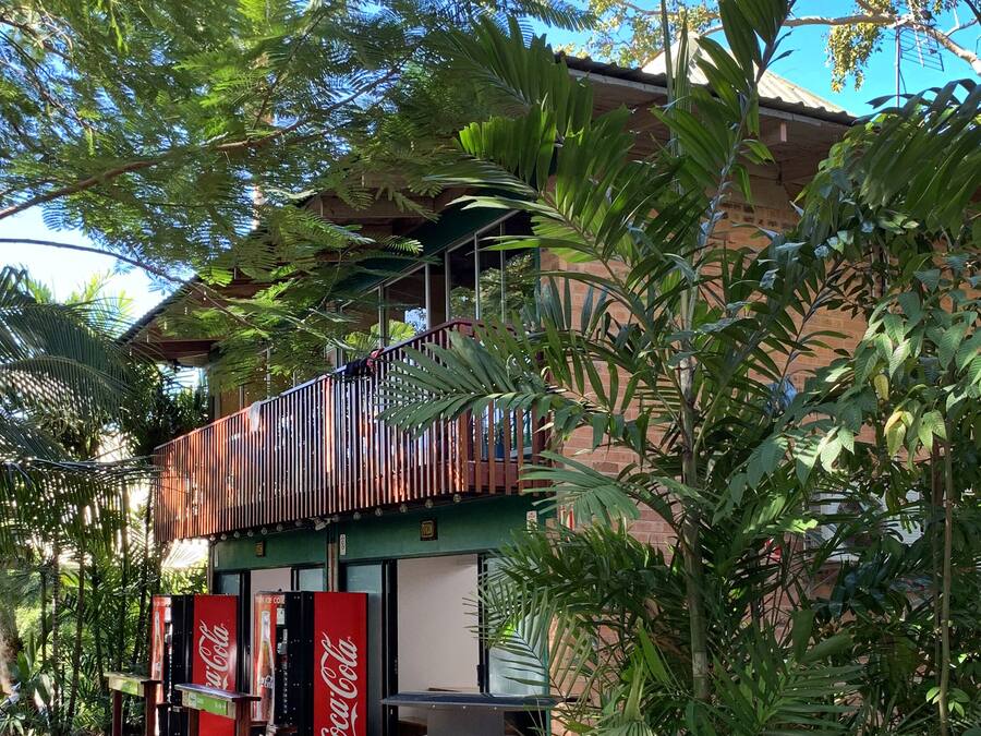 A building with a balcony, surrounded by lush greenery.