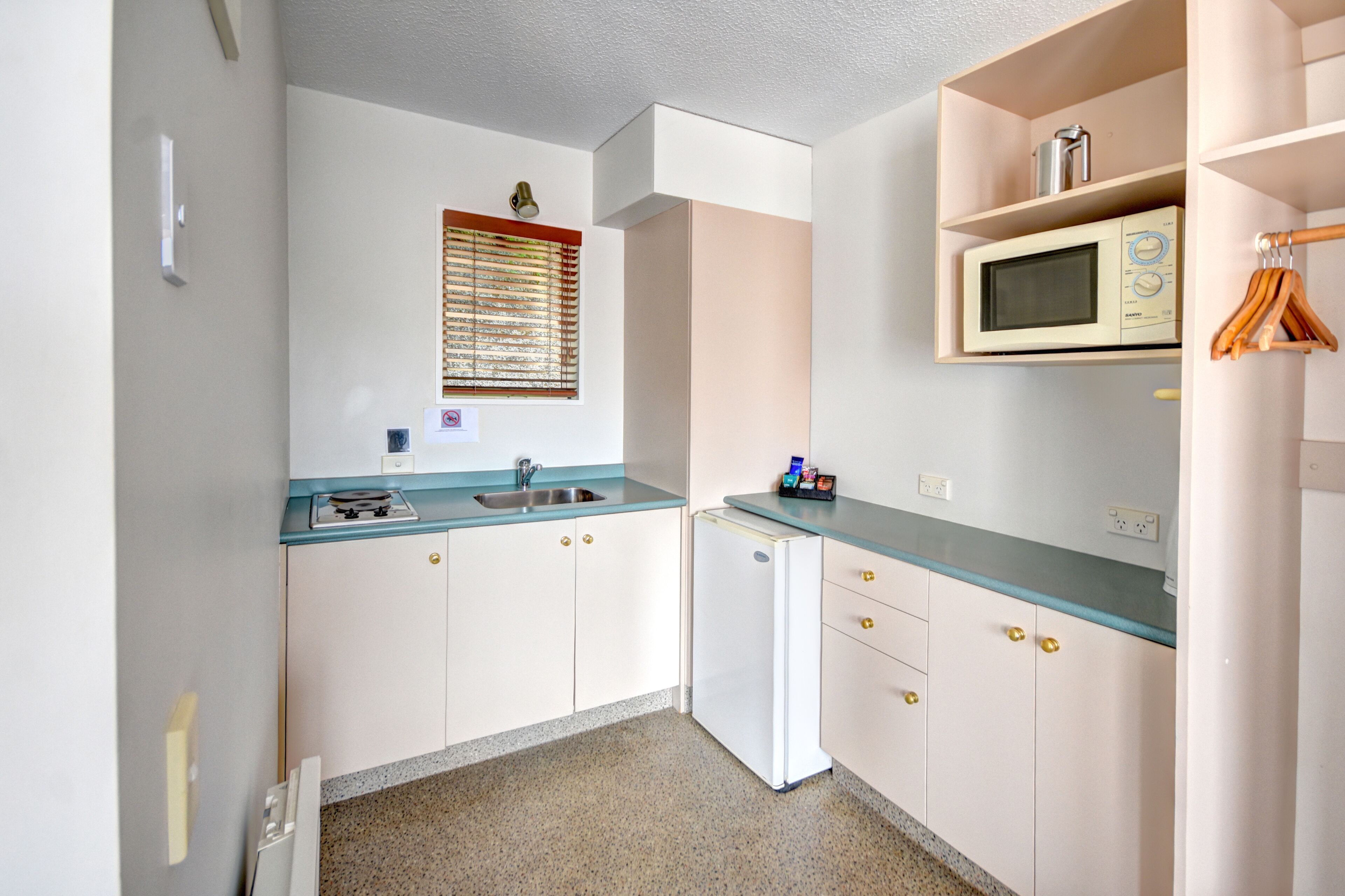 A compact kitchen with a sink, stove, and microwave.