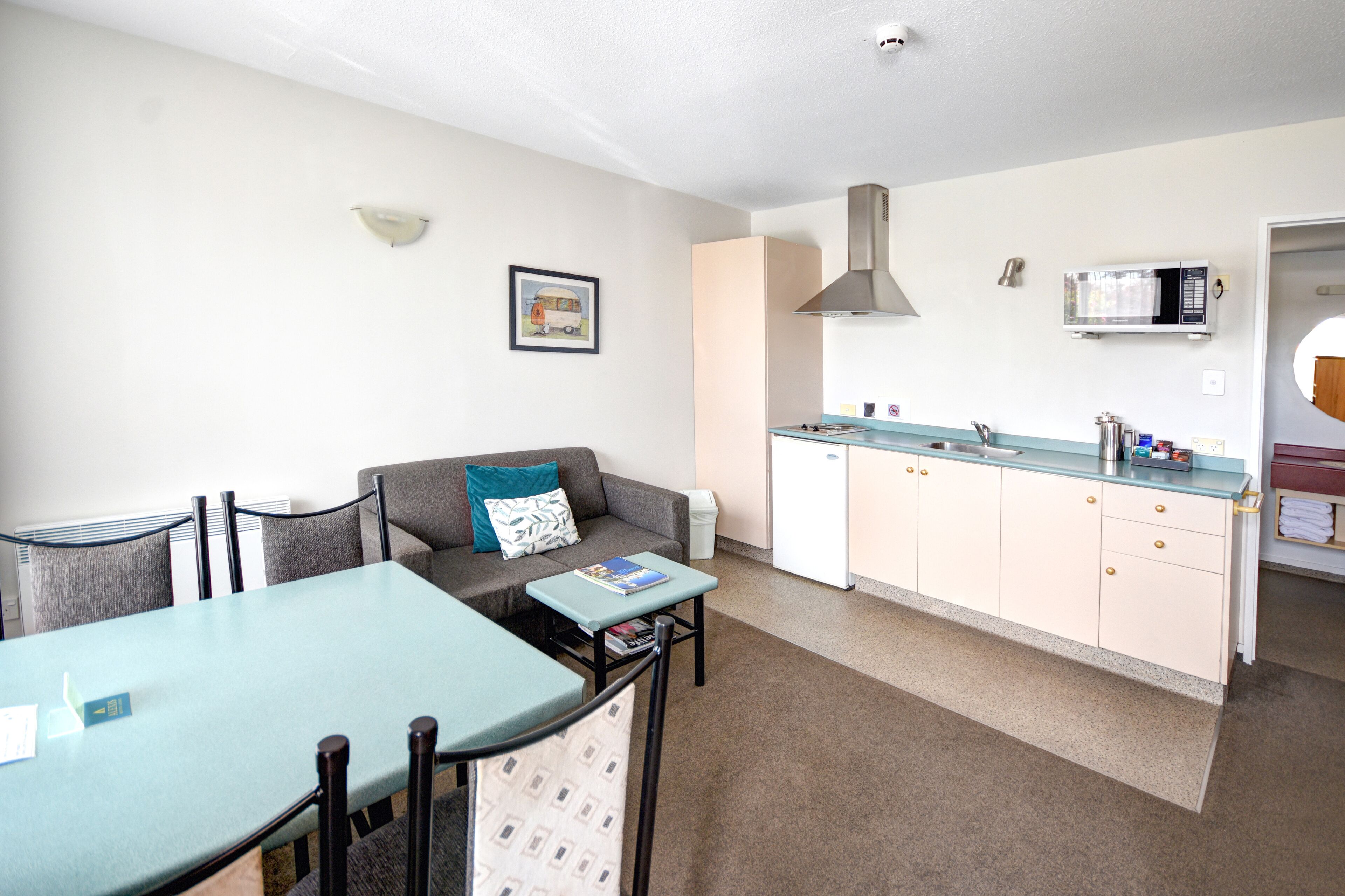 A compact living space with a kitchenette, a dining area, and a sofa with a pillow.
