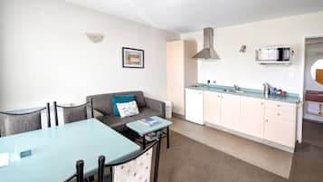 A compact living space with a kitchenette, a dining area, and a sofa with a pillow.