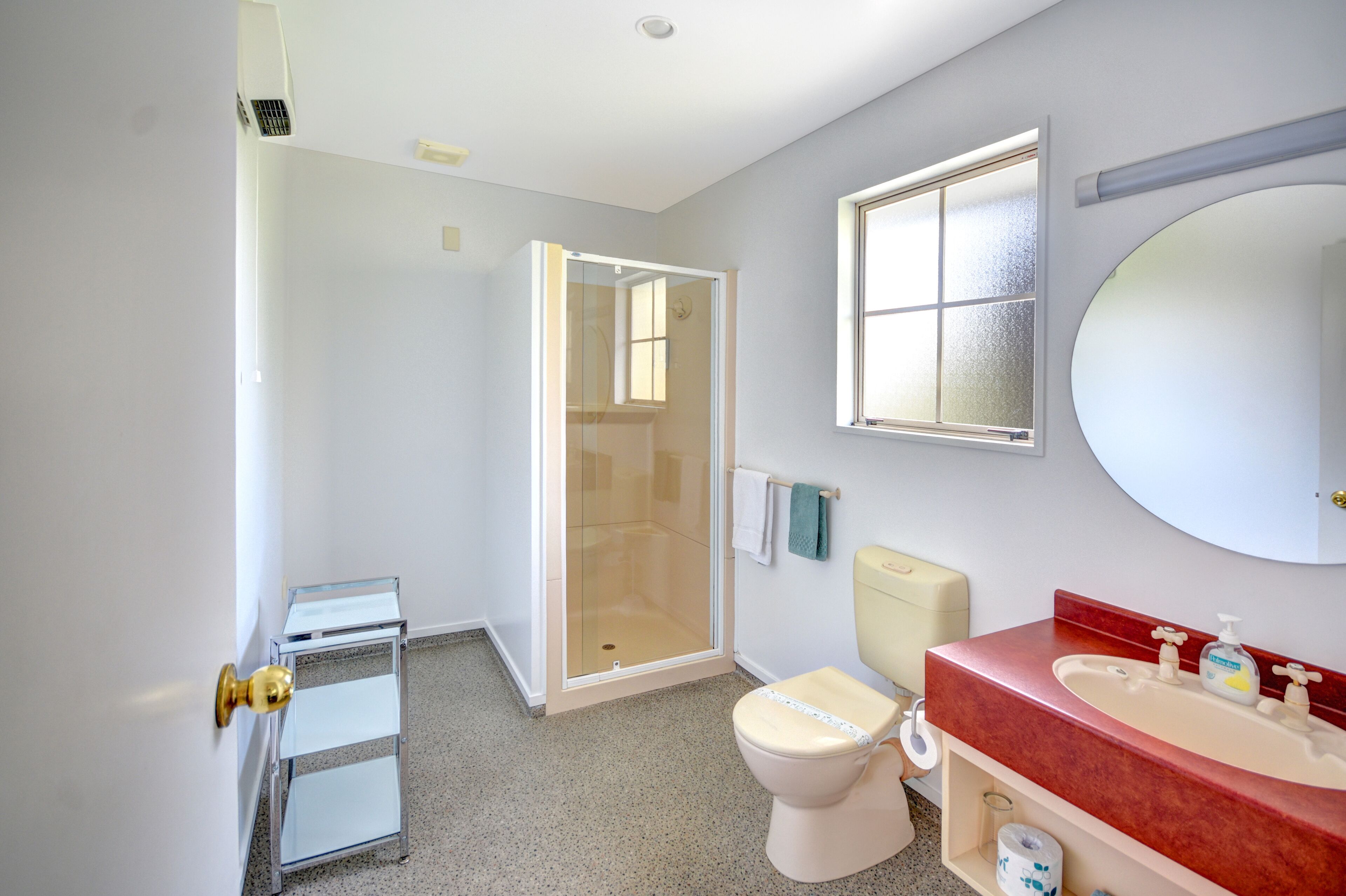 Une salle de bain avec une douche, des toilettes, un lavabo et un petit miroir.