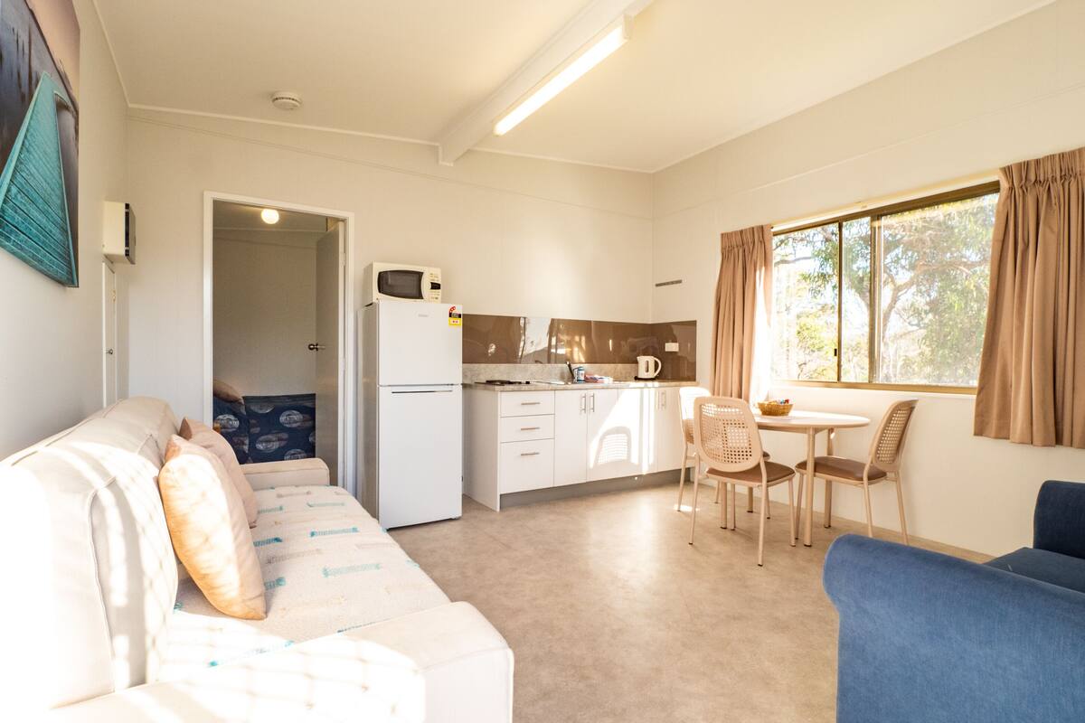 A compact living space with a kitchenette, a dining area, and a seating area with a sofa and chairs.