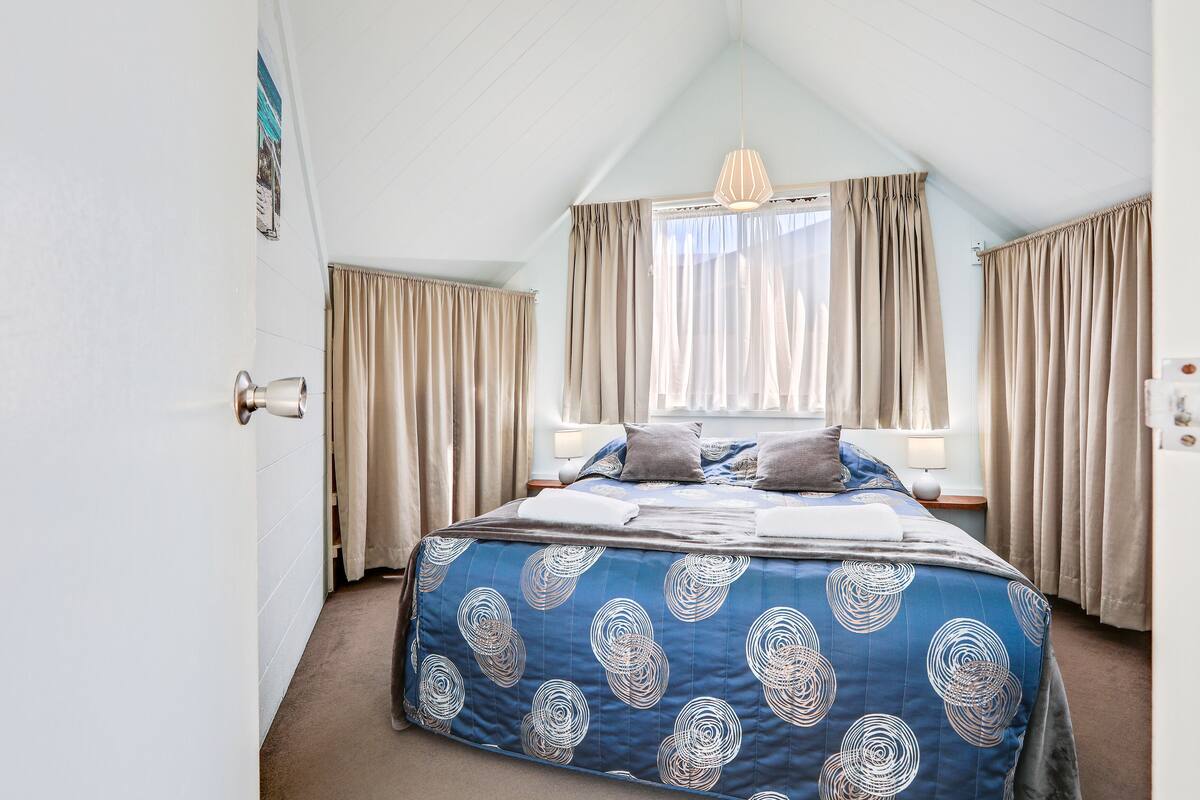 A bedroom with a bed, curtains, a window, and a ceiling light.