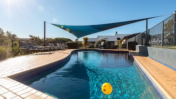 Una piscina al aire libre, sombrillas