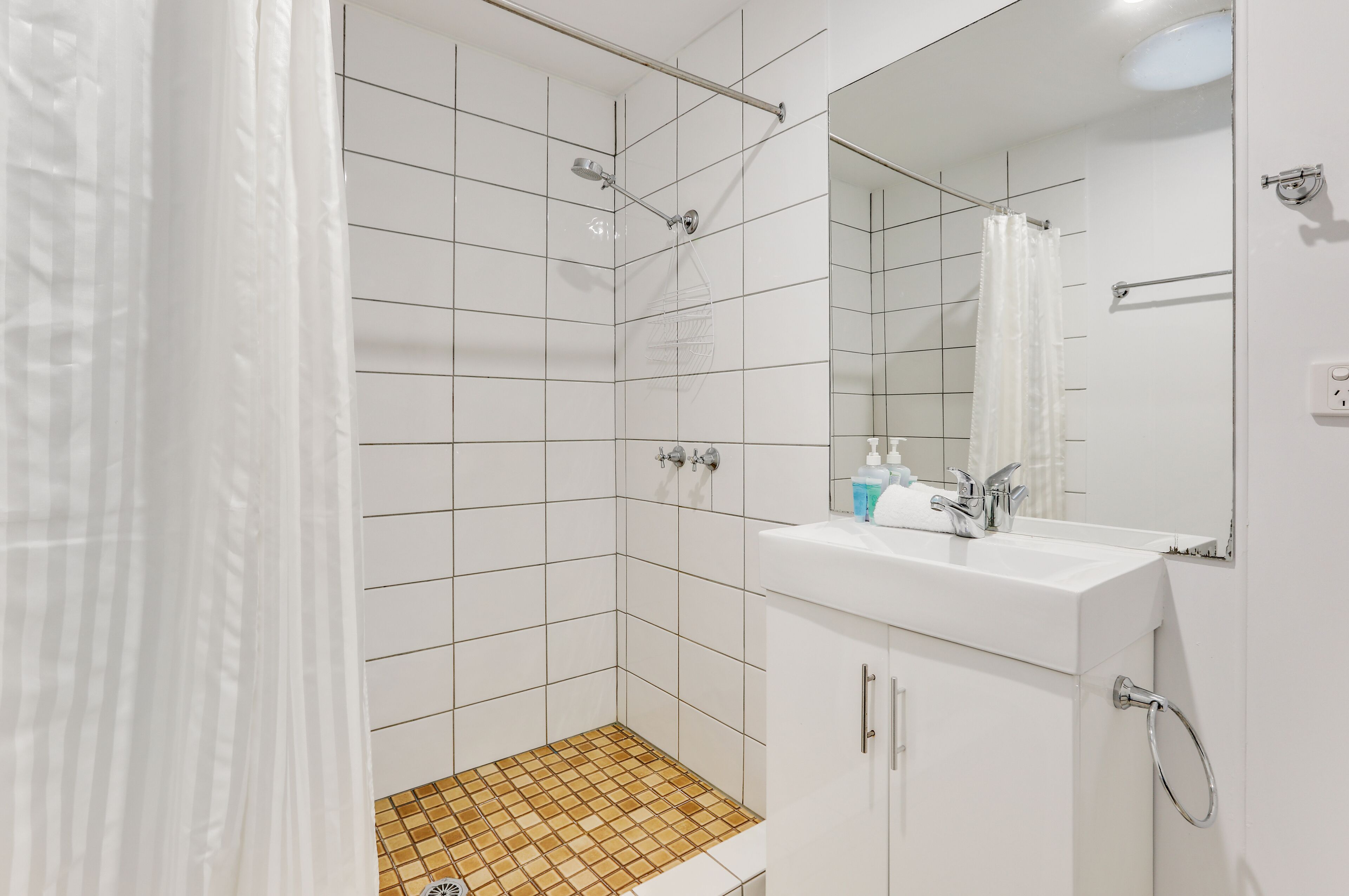 A modern bathroom with a shower, a sink, and a mirror.