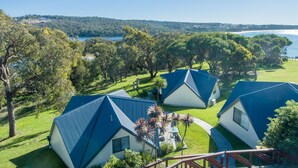 A view of a resort with multiple blue-roofed cottages surrounded by lush greenery and a lake.