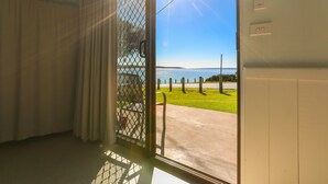 A room with a large window overlooking a grassy area and a body of water.