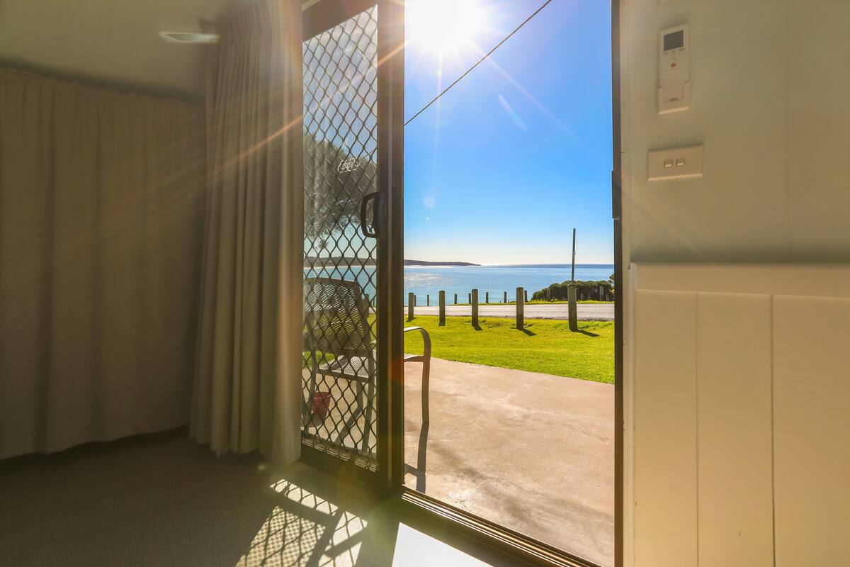 A room with a large window overlooking a grassy area and a body of water.